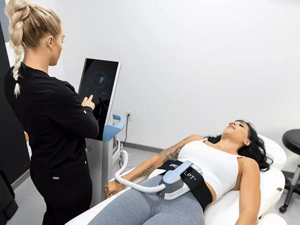 Patient receiving CoolSculpting treatment on the abdomen with applicators in place while a clinician monitors the device.